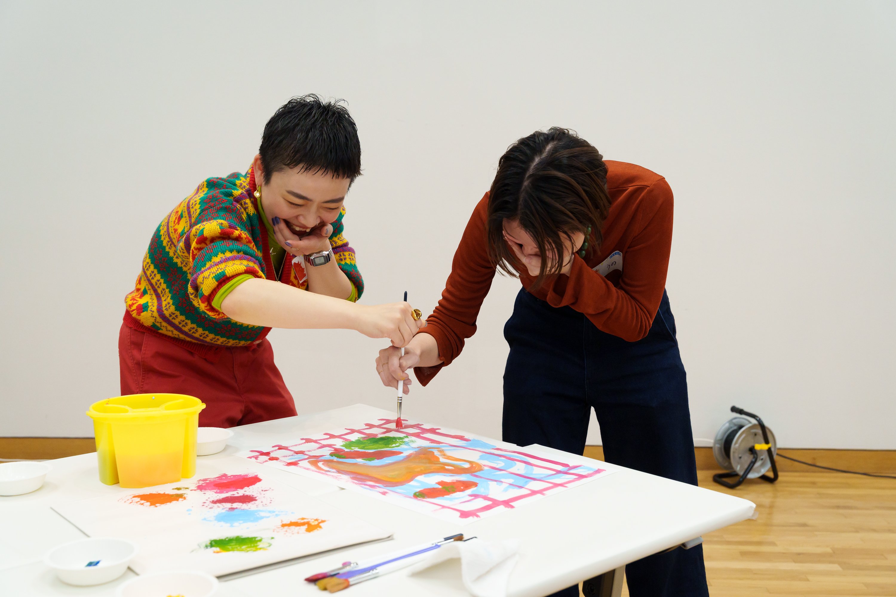 笑いを押さえるようにして、二人で協働して描いている姿