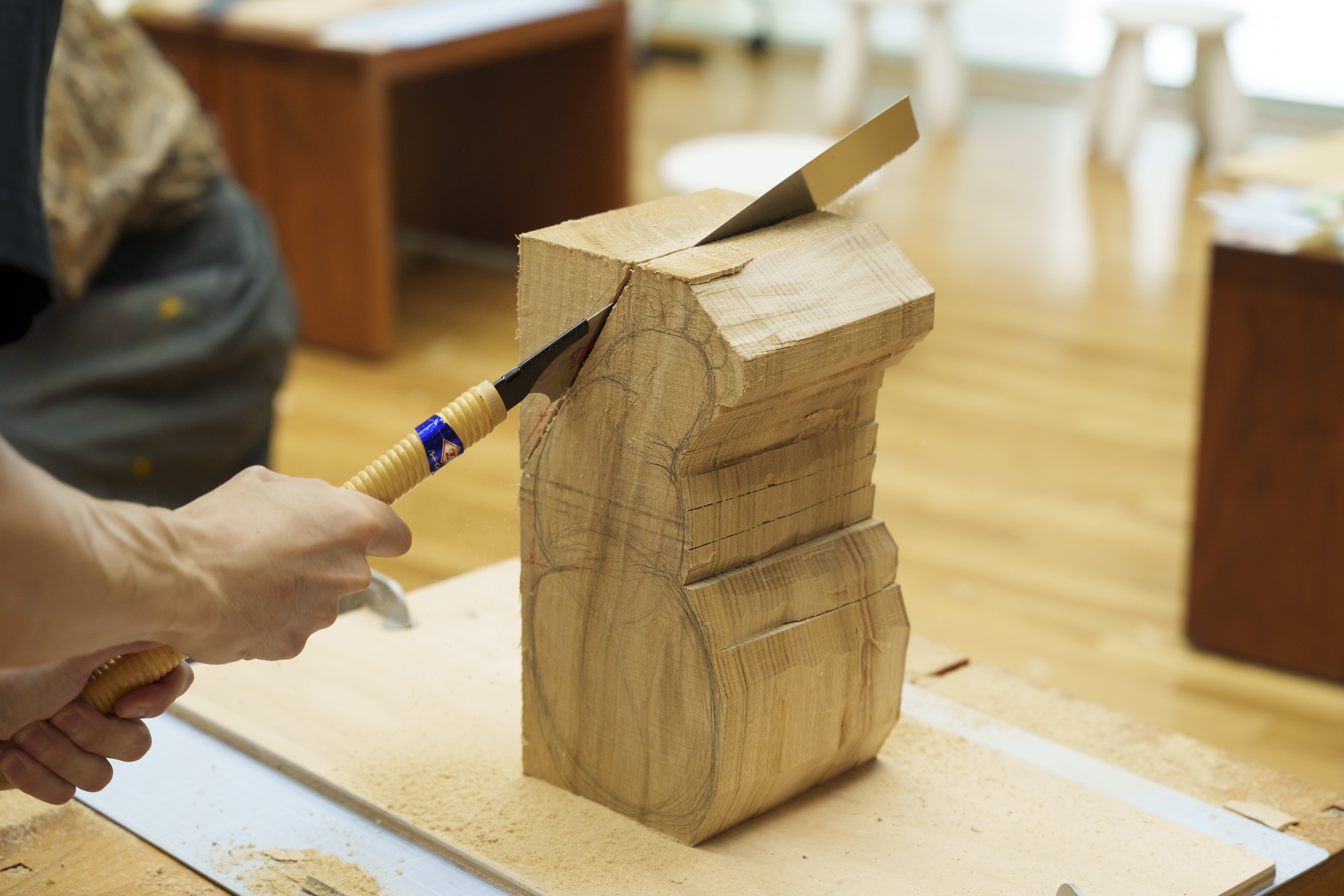 木のかたまりをノコギリで切っている様子